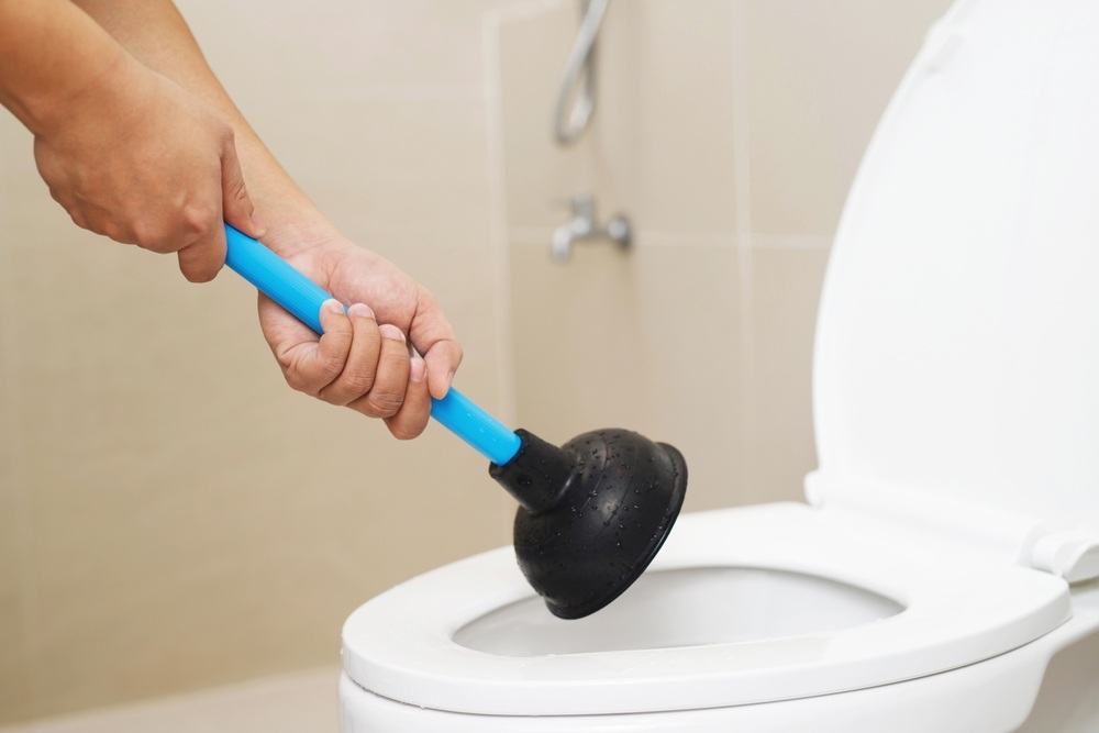 plunging clogged toilet with rubber cup