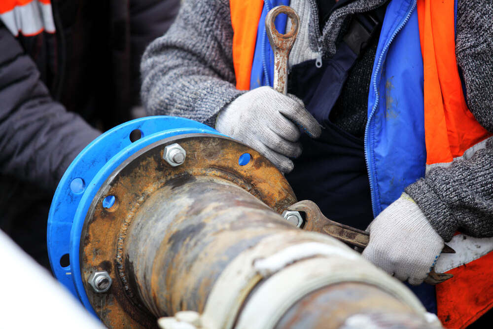 worker tightening bolts on pipe flange